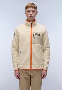 Fleece jacket in cream with orange zipper, two pockets, and a chest pocket. Features a high collar and textured fabric for warmth.