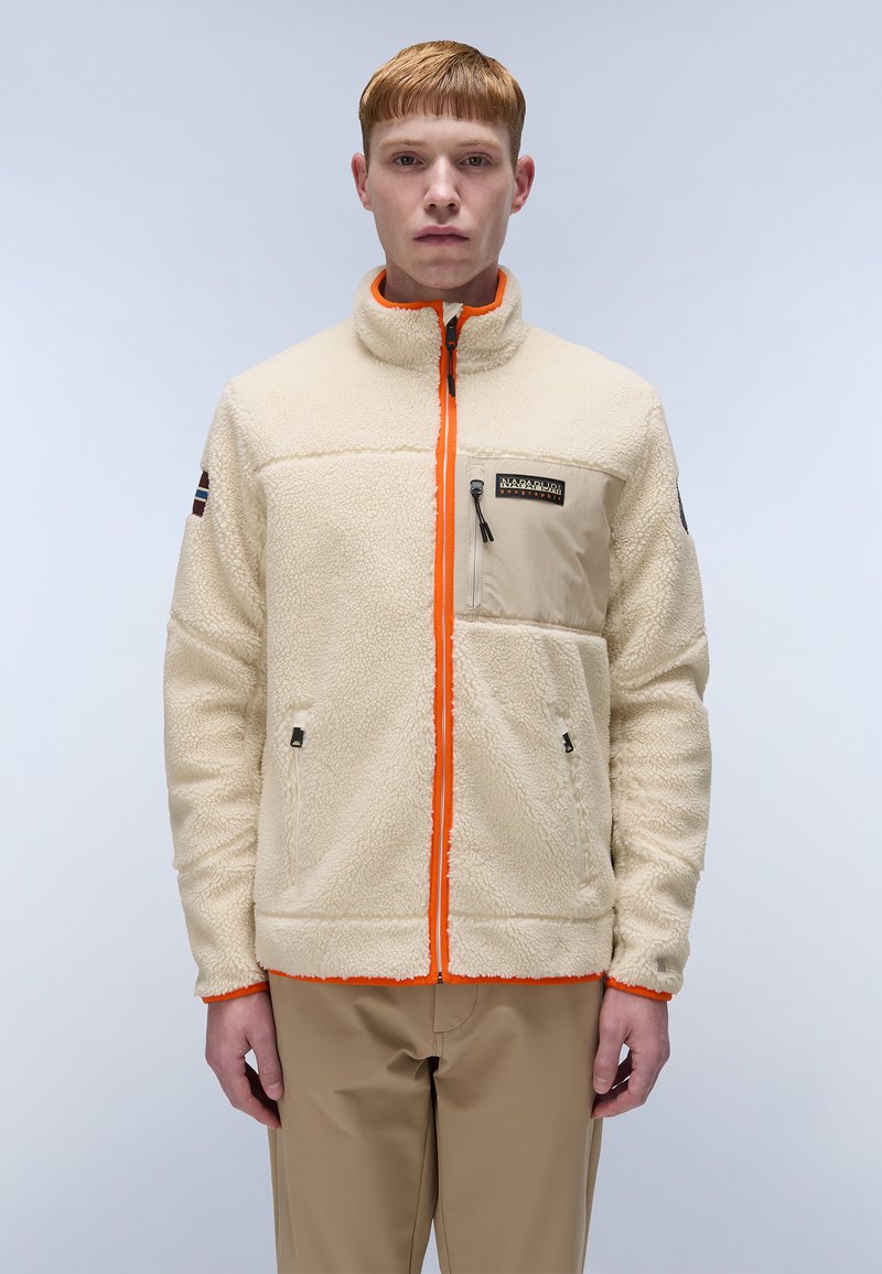 Fleece jacket in cream with orange zipper, two pockets, and a chest pocket. Features a high collar and textured fabric for warmth.