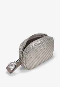 Bolso cosmético tejido de metal plateado con cierre de cremallera, bordes redondeados y una correa de muñeca de tela. Presenta una superficie texturizada y un forro suave.