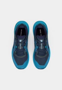 Chaussures de course bleu et bleu marine foncé avec une tige en mesh, un motif texturé et un logo sur la languette. Les lacets sont gris foncé.