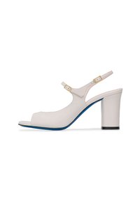 Décolleté color beige in pelle, con punta a forma curva e tacco a blocco, suola blu e dettagli in hardware color oro sulla cinghia della caviglia.