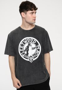 Gray cotton t-shirt featuring a circular white graphic with a penguin in a top hat and "Fleetwood Mac Tour '82" text. Short sleeves, relaxed fit.