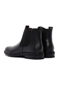 Botas Chelsea de cuero negro con paneles laterales elásticos y tiras en el bucle. Punta redondeada, tacón bajo apilado, acabado liso y acentos texturizados.