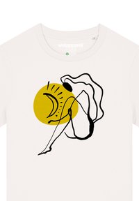 Crème-kleurige t-shirt met een zwarte lijntekening van een figuur met een vloeiende omtrek en een gele cirkel op de achtergrond.