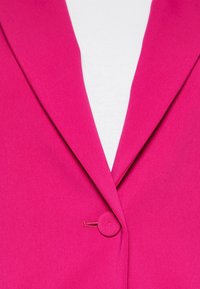 Fuchsia blazer med en figursydd design, skarpa slag och en rund knappstängning för säker fastsättning. Slät tygkänsla.