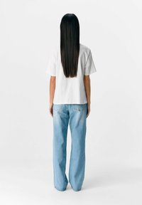 Vit bomullströja med korta ärmar, parat med ljusblå högmidjade jeans med fem fickor och en avslappnad passform.