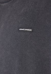Dark gray t-shirt made of soft fabric, featuring a small white "Under Armour" logo on the left chest area. Classic crew neck design.