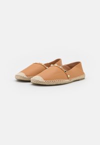 Espadrillas slip-on color tan con upper in pelle testurizzata, dettagli in corda di paglia attorno alla suola e accenti a piramide in metallo sul vamp. 