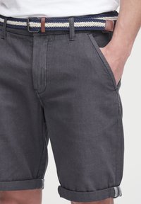 Gray cotton shorts with rolled hems, side pockets, and a navy and cream braided belt featuring a brown leather accent.