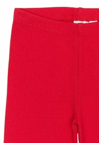 Červené žebrované Leggings s elastickým pasem. Tkanina má jemný, texturovaný vzhled a vertikální pruhy. Bez viditelných zapínání.