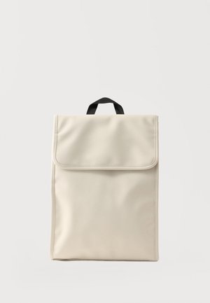 Rucsac dreptunghiular minimalist de culoare crem, cu mâner negru în partea de sus și închidere cu clapetă, pe un fundal deschis.