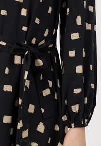 Μαύρο φόρεμα με μπεζ μοτίβο βούρκας, ελαφρύ ύφασμα, μακριά μανίκια με ελαστικούς σφιγκτήρες και ζωνάκι από ύφασμα στη μέση.