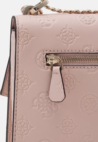 Section de sac en cuir rose clair avec motifs floraux embossés, fermeture éclair dorée, tirette en cuir assortie et détail de chaîne en or.