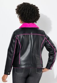 Zwarte leren jas met een roze nepbont kraag en roze stikdetails, met een aansluitend ontwerp en lange mouwen.