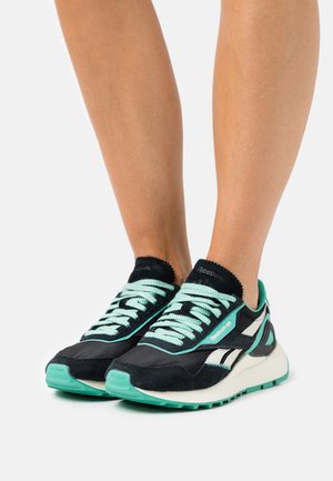 Des chaussures de sport noires et turquoise avec un tissu texturé, des lacets contrastants et un col rembourré ; composées d'un mélange de daim et de matériaux en maille.