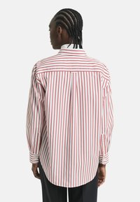 Red and white striped shirt, featuring a classic collar, long sleeves, and a back pleat. Made of smooth cotton fabric with a tailored fit.