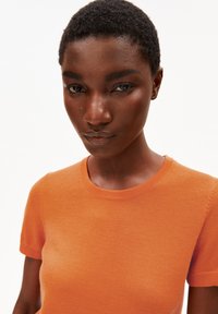 Korte mouwen oranje gebreide top met een ronde halslijn, een gladde textuur en een aansluitend ontwerp. Effen stof zonder patronen of accenten.