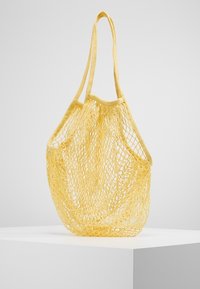 Gele nettas met twee schouderbanden, met een open ontwerp en een lichtgewicht textuur, geschikt voor het dragen van verschillende voorwerpen.