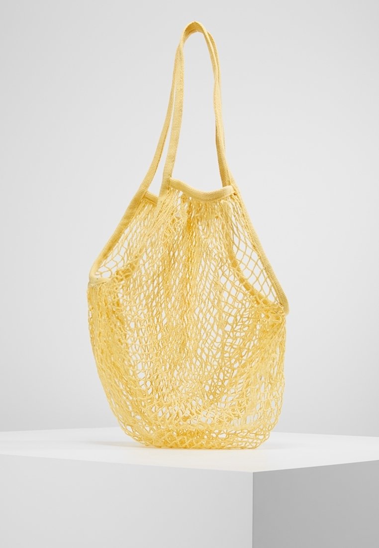Gele nettas met twee schouderbanden, met een open ontwerp en een lichtgewicht textuur, geschikt voor het dragen van verschillende voorwerpen.