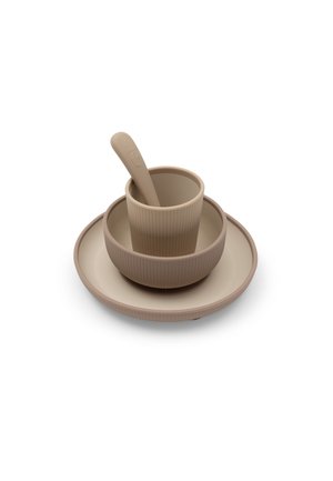 Tasse, bol et assiette beiges en silicone empilés avec une cuillère assortie à l'intérieur de la tasse.