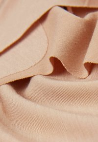 Ljusrosa tyg med en slät textur, med mjuka veck och subtila diagonala vävningar. Kanterna är snyggt avslutade med en fin söm.