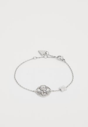 Silver chain bracelet featuring a central decorative element with a large stone surrounded by smaller stones, finished with a clasp and charm.