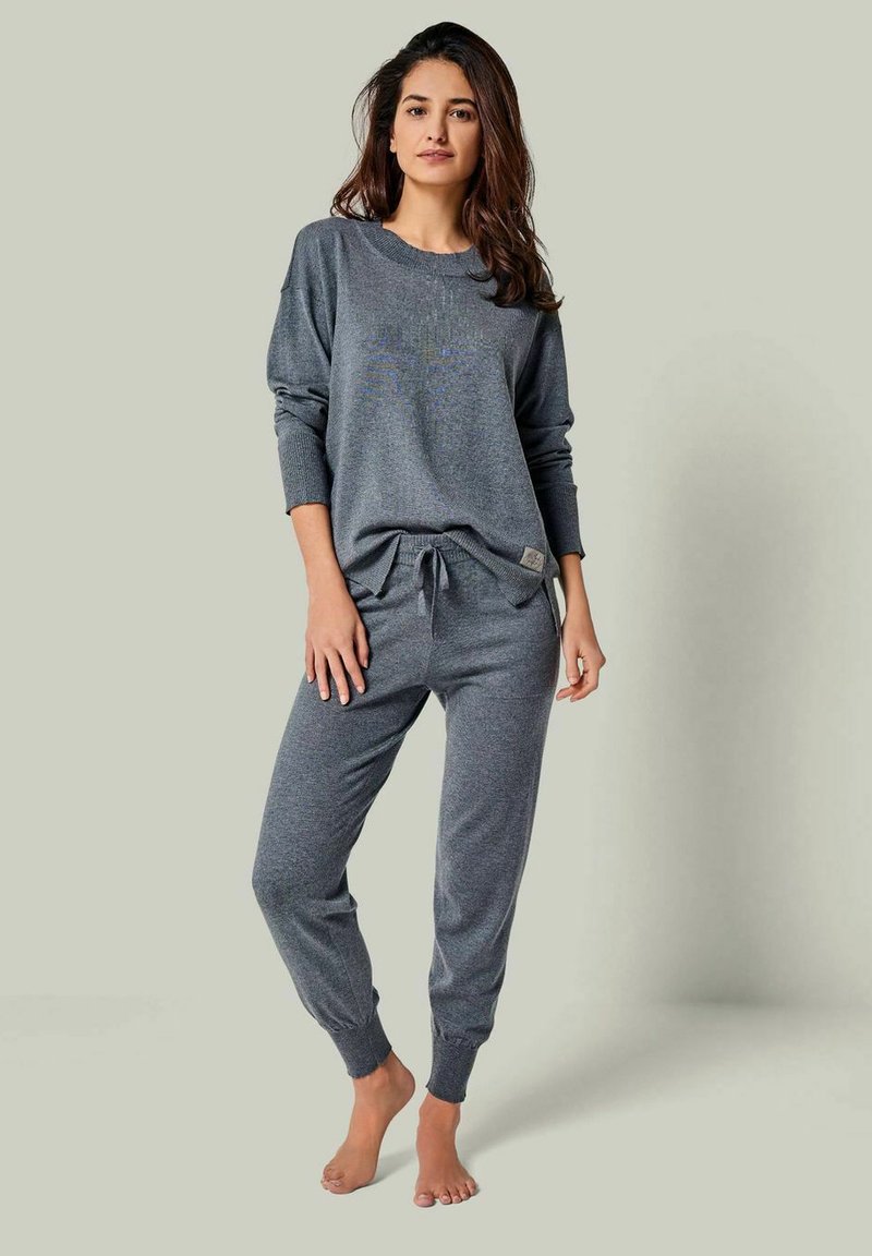 Grau Freizeitkleidung-Set besteht aus einem locker sitzenden Langarmoberteil und Jogginghosen. Weicher Stoff, gerippte Bündchen und eine verstellbare Kordelzugtaille.
