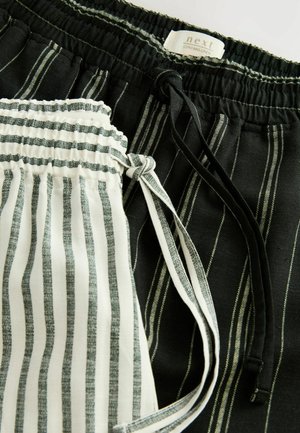 Pantalons à cordon de serrage en noir et blanc ; le noir présente des rayures fines, tandis que le blanc a des rayures grises plus larges. Tissu léger, ceintures élastiques.