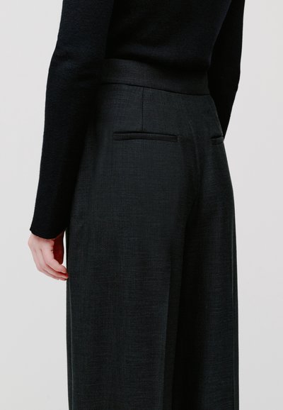 Spodnie w kolorze węglowo-szarym, dopasowane, o gładkiej fakturze, prostym kroju i dwóch tylnych kieszeniach. Minimalistyczny design z płaskim paskiem w talii.