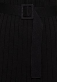 Czarna dzianina z pionowym ryflem, pasujący pasek z kwadratową klamrą oraz gładkie, płaskie wykończenie.