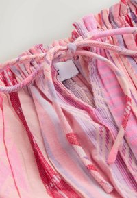 Gros plan sur un tissu rayé rose et violet avec une ceinture élastique froncée et un cordon de serrage attaché.