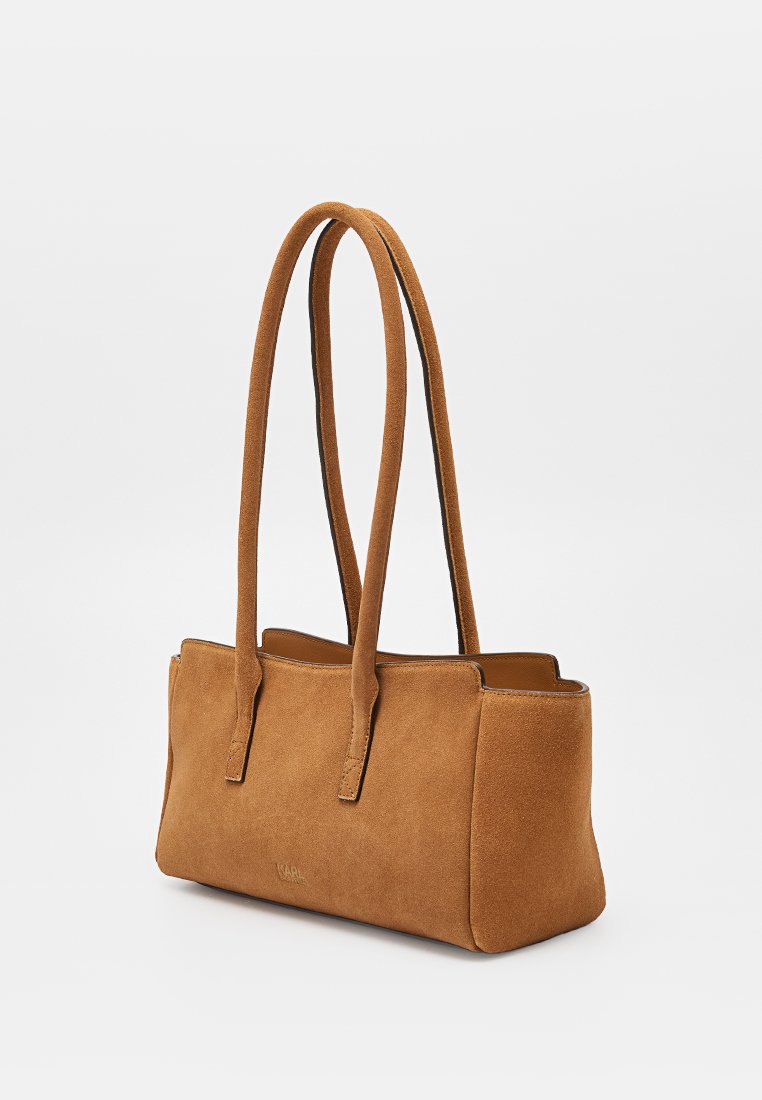 Bolso rectangular marrón de ante con largas dobles asas para el hombro, parte superior ligeramente abierta y un sutil grabado de la marca en el centro frontal.
