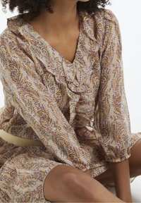 Vestido ligero y estampado en tonos pastel, con volantes, escote en V y mangas de tres cuartos. Tejido suave con un delicado diseño floral.