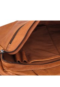Interno di una borsa in pelle marrone caratterizzato da una tasca con zip, una texture liscia e un ampio scomparto con più slot per carte.