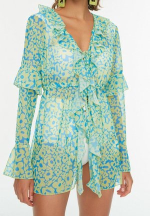 Transparentes langärmliges Blumen Kleid mit gerafftem Ausschnitt und Ärmeln in Blau und Blassgelb, über weißen Shorts getragen.