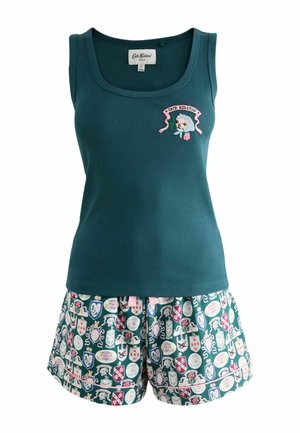 Haut sans manches bleu sarcelle foncé avec petit chat brodé et blason floral au-dessus d’un short à motifs avec bouclier et motifs floraux en vert, rose et blanc.