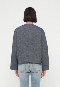 Σκούρο μπλε, cropped μάλλινο σακάκι με στρογγυλή λαιμόκοψη και φαρδιά μανίκια. Λεία υφή, απλό σχέδιο, κατάλληλο για φορεματισμό πάνω από άλλα ρούχα.