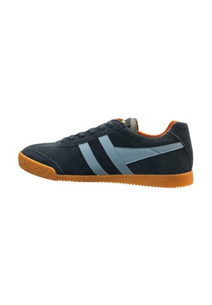 Zapatilla de ante azul oscuro con rayas laterales azul claro, forro interior naranja y suela de goma color caramelo, mostrada de perfil mirando hacia la izquierda.
