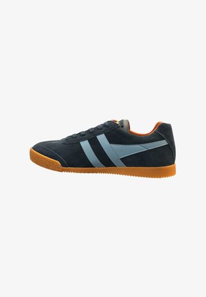 Zapatilla de ante azul oscuro con rayas laterales azul claro, forro interior naranja y suela de goma color caramelo, mostrada de perfil mirando hacia la izquierda.