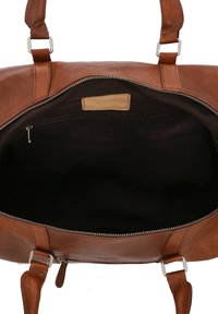 Hnedá kožená taška typu duffel so zipsovým zatváraním; má dve pevné rúčky a vnútornú vrecko na zips pri čiernej látkovej podšívke.