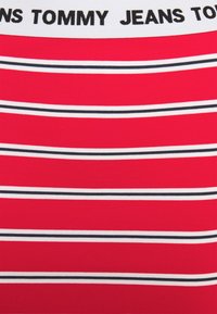 Rot gestreiftes Oberteil mit weißen und schwarzen horizontalen Streifen. Verfügt über ein weißes Band oben mit schwarzem Schriftzug "TOMMY JEANS."