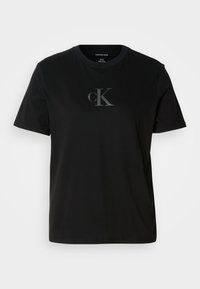 Crna pamučna majica kratkih rukava s diskretnim sivim cK logom na prsima. Okrugli izrez i opušteni kroj s ravnim rubom.