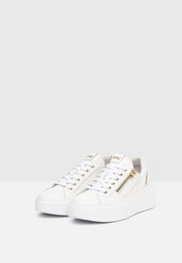 Weiße Plateausneaker mit glatter Oberfläche, goldenen Hardware-Details, Schnürung und seitlichem Reißverschluss für einfachen Tragekomfort.