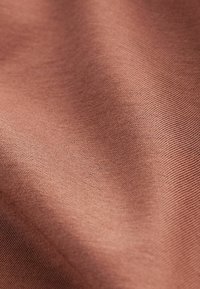 Țesătură moale de culoare teracotă caldă, cu o textură subtilă, evidențiată printr-un model fin și o cădere netedă. Ideală pentru îmbrăcăminte sau tapițerie.