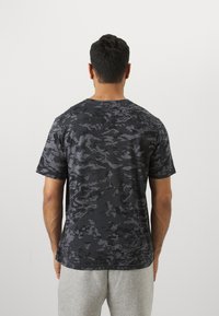 Kortærmet sort camo t-shirt med en struktureret overflade. Crew neck-design og afslappet pasform, lavet af blødt stof for komfort.