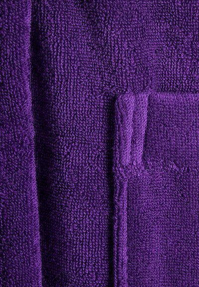 Tissu en éponge violet avec une surface texturée. Doté d'une qualité douce et absorbante avec un bord soigneusement cousu et une couture de poche visible.