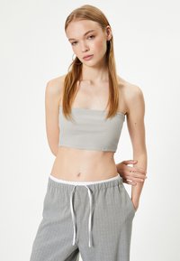 Top corto de canalé gris claro con escote recto, combinado con pantalones grises a rayas con cintura elástica y cordón ajustable.