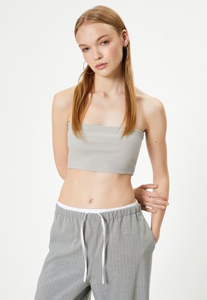 Top corto de canalé gris claro con escote recto, combinado con pantalones grises a rayas con cintura elástica y cordón ajustable.