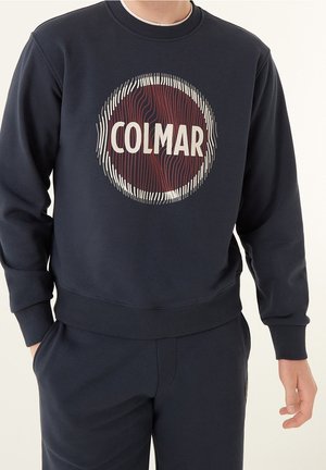 Sweatshirt bleu foncé avec un graphisme circulaire bourgogne et blanc portant le texte "COLMAR" en lettres grasses. Tissu doux et texturé.