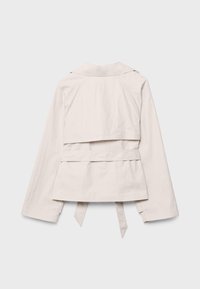 Lichtbeige lange mouwen jasje met kraag, achterpand-detail en een tailleceintuur die naar beneden hangt, plat uitgestald tegen een witte achtergrond.